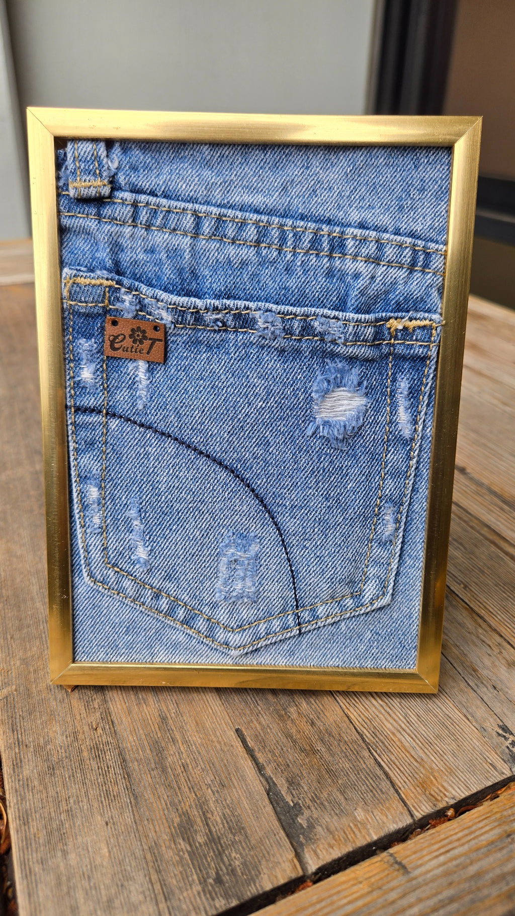 Denim pocket gold frame display with black glasses