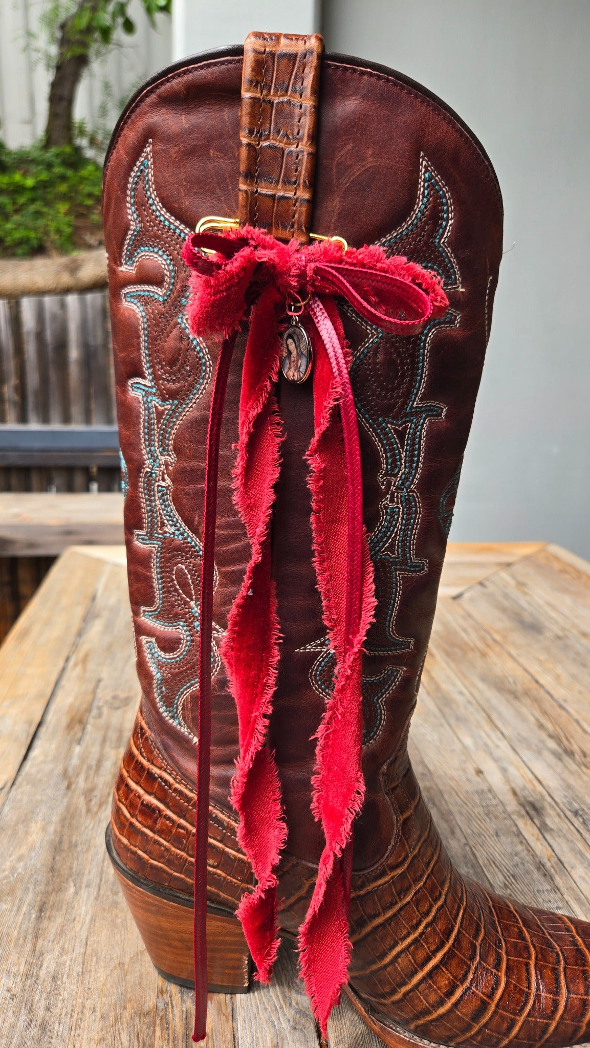 Red ribbon western boot charm on brown cowboy boot